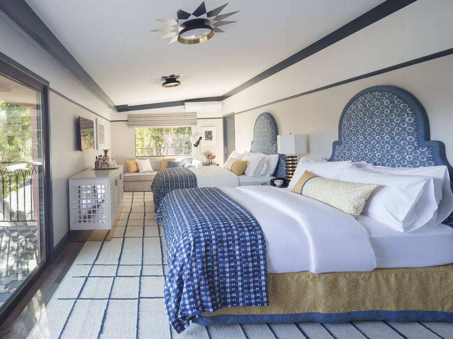 A modern hotel room with a large bed, a seating area with a view, and a balcony.