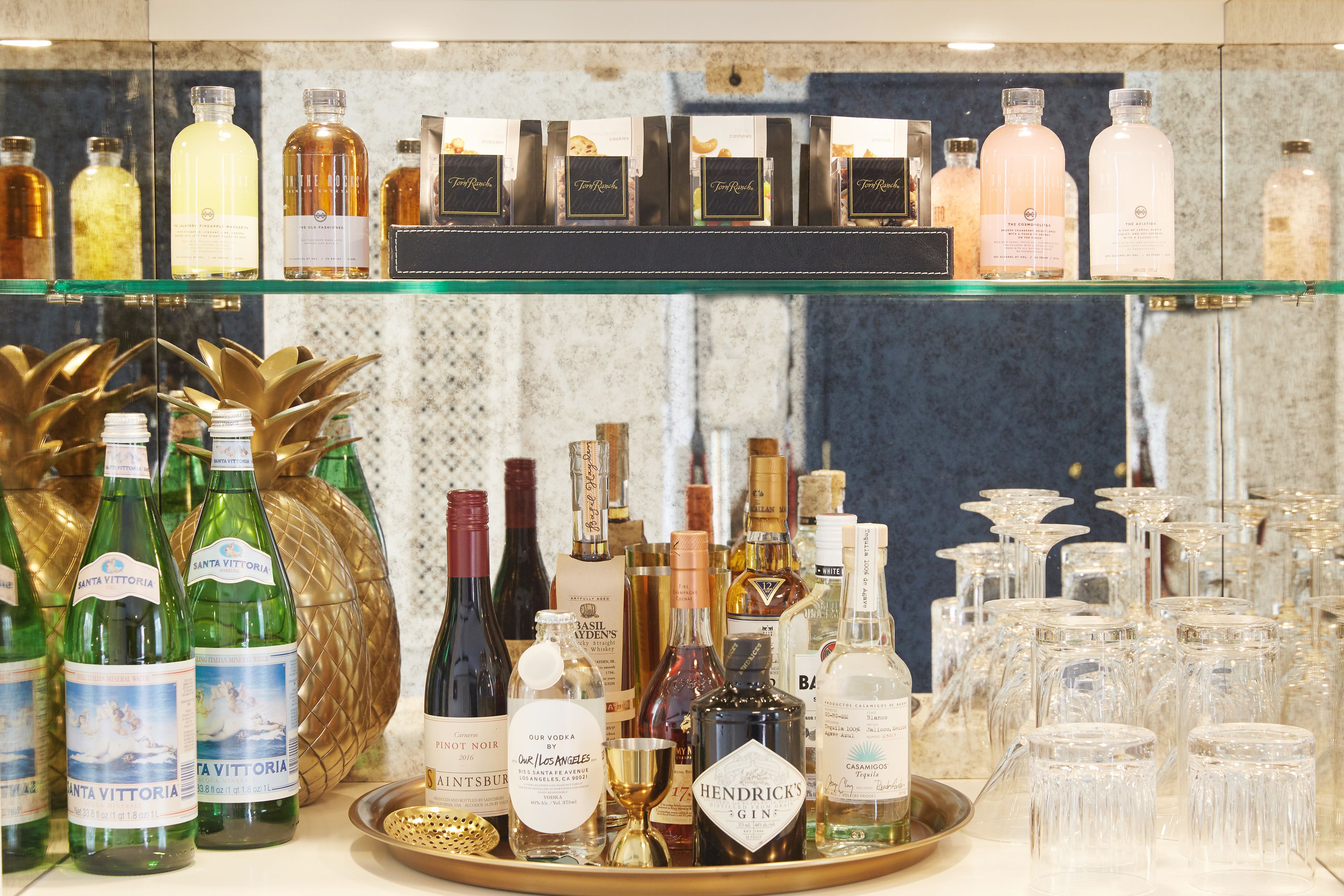 A display of various liquor bottles and glasses on shelves and a tray.