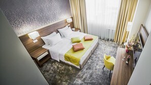 Una habitación de hotel con una cama grande, mesitas de noche, un escritorio y una silla.
