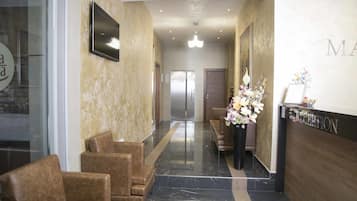 A reception area with a reception desk, seating, and a hallway leading to a door.