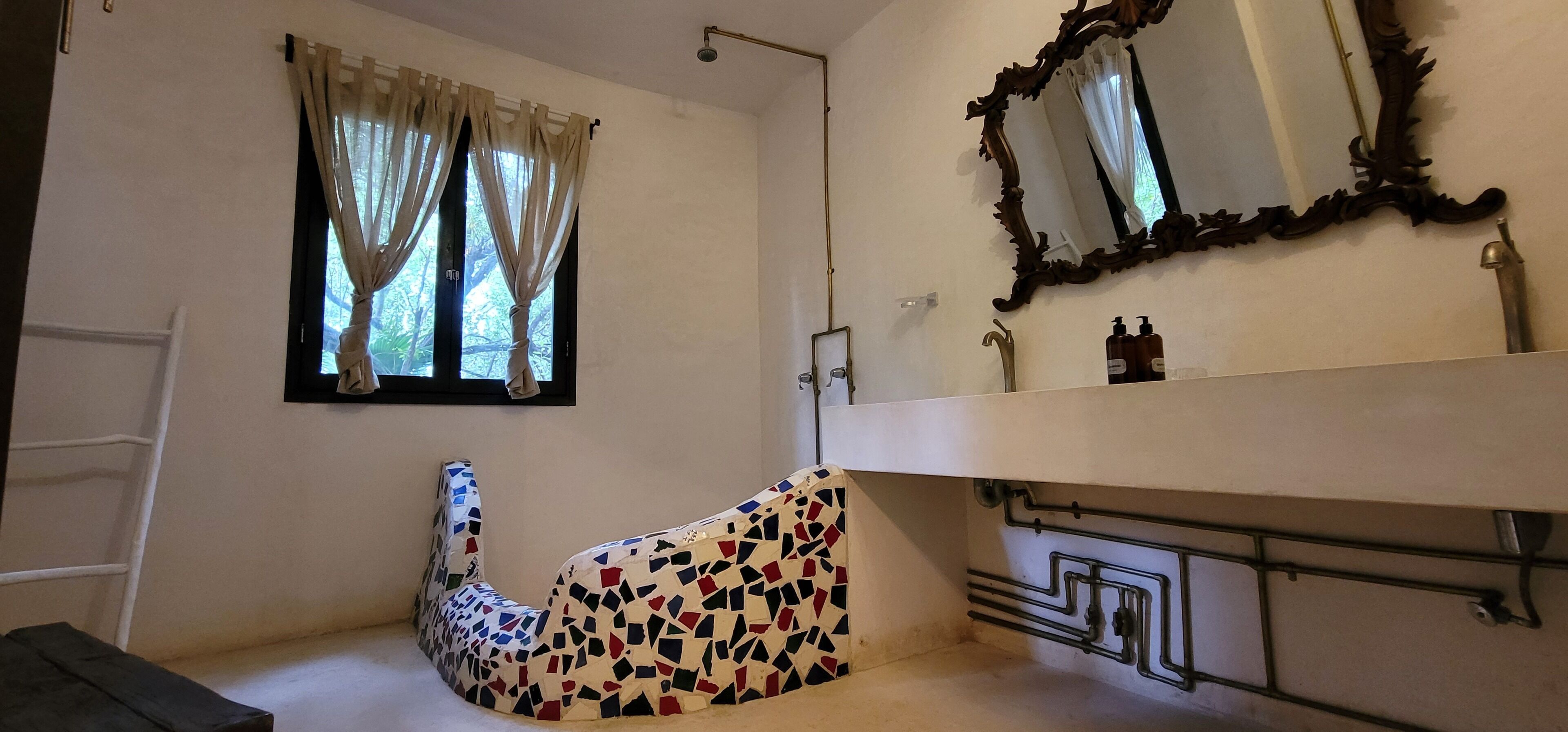 A bathroom with a white sink, a mirror with an ornate frame, and a shower.