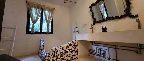 A bathroom with a white sink, a mirror with an ornate frame, and a shower.