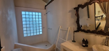 Une salle de bain avec une douche, une fenêtre, un miroir et un lavabo.