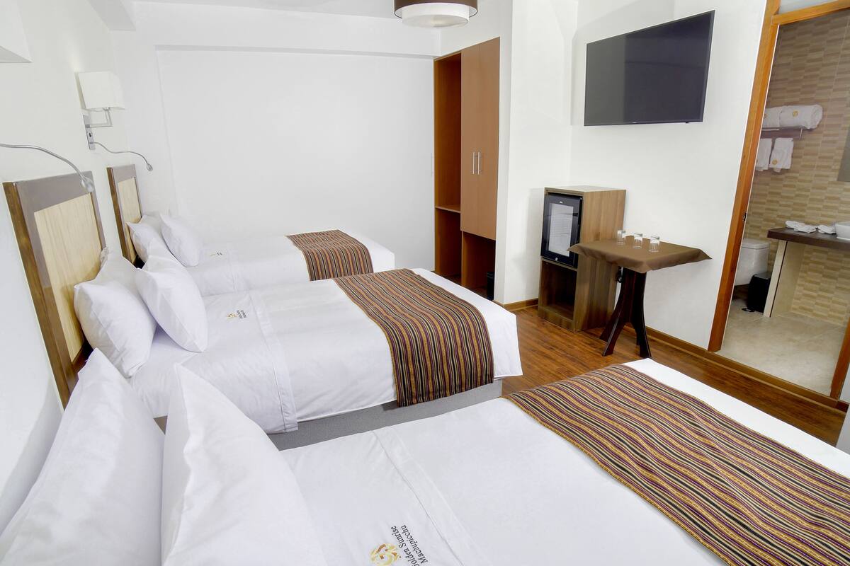 A hotel room with two beds, a TV, a desk, and a mirror.