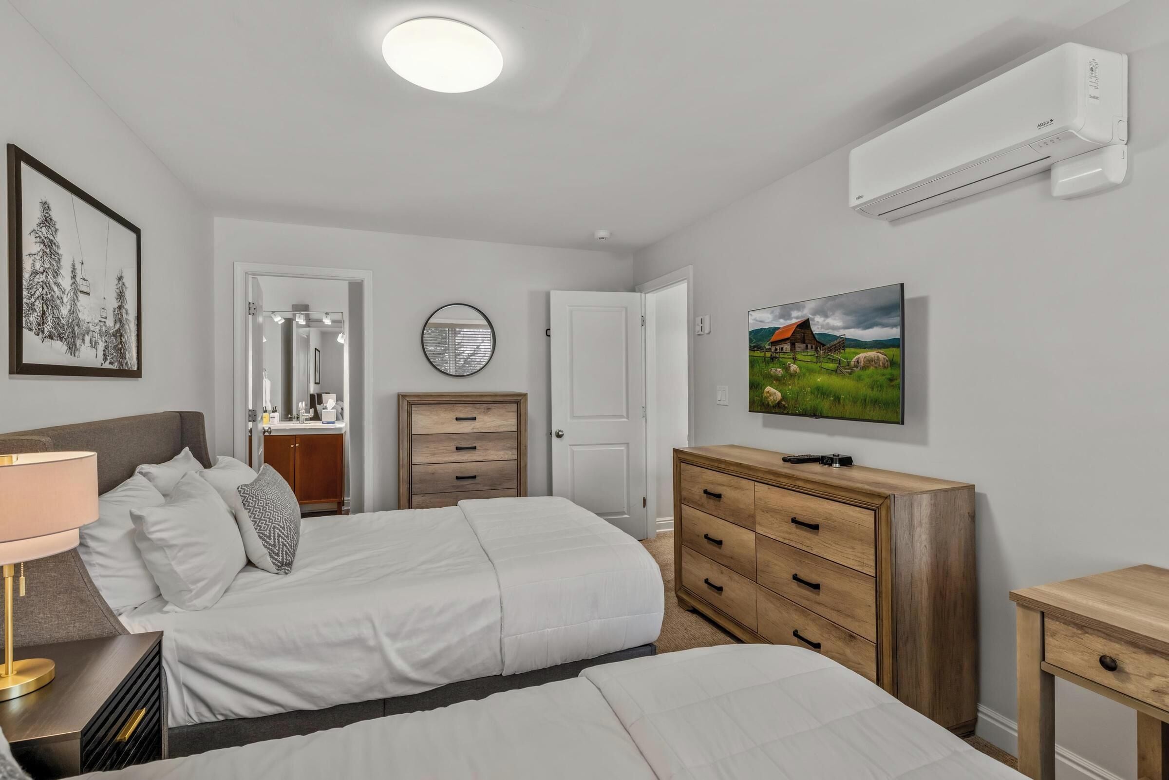 A bedroom with two beds, a dresser, a TV, and an air conditioner.