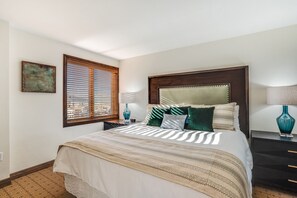 A neatly arranged bedroom with a large bed, a nightstand, a lamp, and a window with blinds. - Bear Claw 209 Premium On Mountain Condo With Ski-In/Ski-Out Access! (Steamboat Springs)