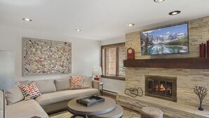 Una sala de estar moderna con una chimenea de piedra, un cuadro abstracto grande y un sofá cómodo.