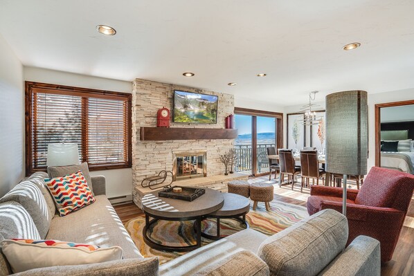 A spacious living room with a fireplace, comfortable seating, and a view of the outdoors. - Bear Claw 209 Premium On Mountain Condo With Ski-In/Ski-Out Access! (Steamboat Springs)