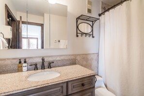 A bathroom with a granite countertop, a sink, a mirror, a towel rack, and a shower curtain. - Bear Claw 209 Premium On Mountain Condo With Ski-In/Ski-Out Access! (Steamboat Springs)