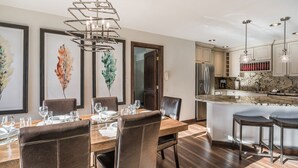 Una cocina moderna con encimera de mármol, electrodomésticos de acero inoxidable y un comedor con mesa de madera y sillas de cuero.