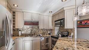 Una cocina moderna con armarios blancos, electrodomésticos de acero inoxidable, encimeras de granito y una alfombra estampada.
