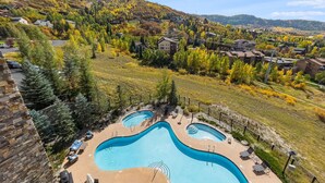A residential area with a swimming pool, houses, and a hilly landscape. - Edgemont 2402 Luxury On Mountain Condo With Ski-In/Ski-Out Access! (Steamboat Springs)