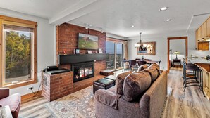 Un amplio salón con chimenea, un ventanal grande y una zona de estar acogedora.