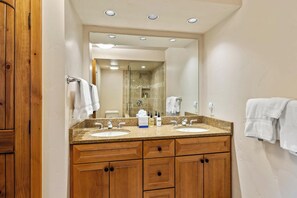 Une salle de bain avec deux lavabos, des meubles en bois et un grand miroir.