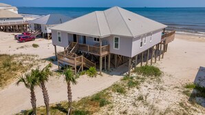 A beachfront house with a balcony, a deck, and a view of the ocean. - Family Tides | Pool, on west end. Nightly Sept stays (Dauphin Island)