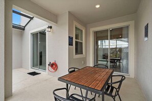 Enjoy casual dining in this outdoor space with a table and chairs, surrounded by a covered patio and skylight.