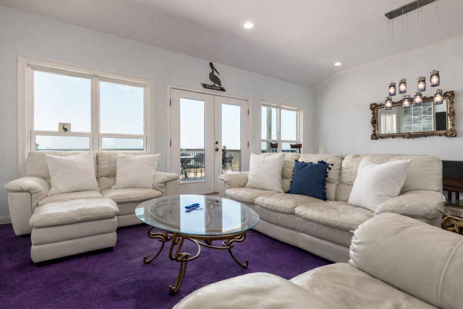 A living room with two sofas, a glass coffee table, and a purple carpet.