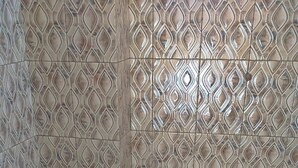 A small bathroom with a toilet, patterned tiles, and a tiled floor. - Homestay in Dar es salaam (DSM)