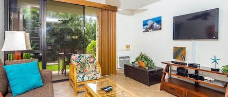 A living room with a sofa, a wicker coffee table, a television, and a ceiling fan.