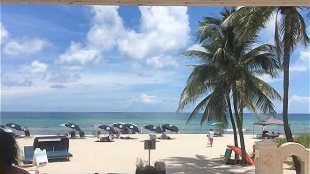 Ein Restaurant direkt am Strand mit Außenbereich, Blick auf das Meer und Palmen.