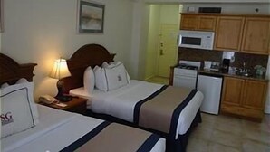 Ein Hotelzimmer mit zwei Betten, einer kleinen Küchenzeile und einer Mikrowelle.