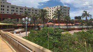 Ein Hotel mit mehreren Etagen, Palmen und einem überdachten Gang.