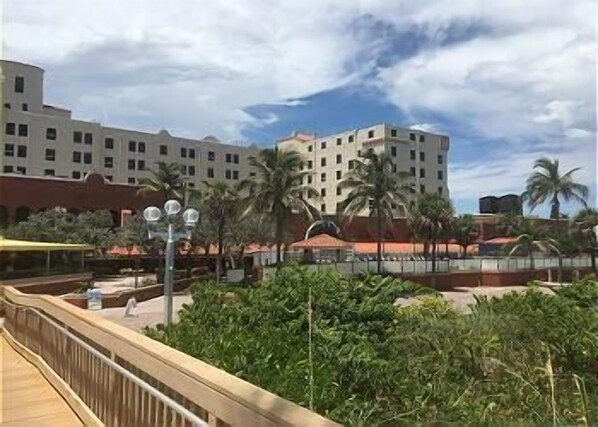 Un hôtel à plusieurs étages, avec des palmiers et une galerie couverte.