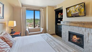 A hotel room with a bed, a fireplace, a TV mounted on the wall, and a view of the outside. - Edgemont 2703 Luxury On Mountain Condo With Ski-In/Ski-Out Access! (Steamboat Springs)