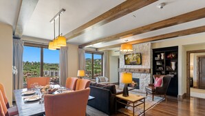 A spacious living area with a dining table set for six, a fireplace, and a view of the outdoors. - Edgemont 2703 Luxury On Mountain Condo With Ski-In/Ski-Out Access! (Steamboat Springs)