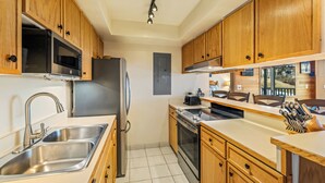 A modern kitchen with wooden cabinets, stainless steel appliances, and a built-in oven. - Bear Claw 203 Premium On Mountain Condo With Ski-In/Ski-Out Access! (Steamboat Springs)