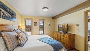 A bedroom with a large bed, a wooden dresser, a television, and a painting on the wall. - Bear Claw 203 Premium On Mountain Condo With Ski-In/Ski-Out Access! (Steamboat Springs)
