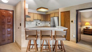 Una cocina moderna con una isla central, taburetes de madera y armarios empotrados.