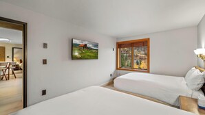Un dormitorio con dos camas, una ventana con vistas al paisaje y un cuadro en la pared.