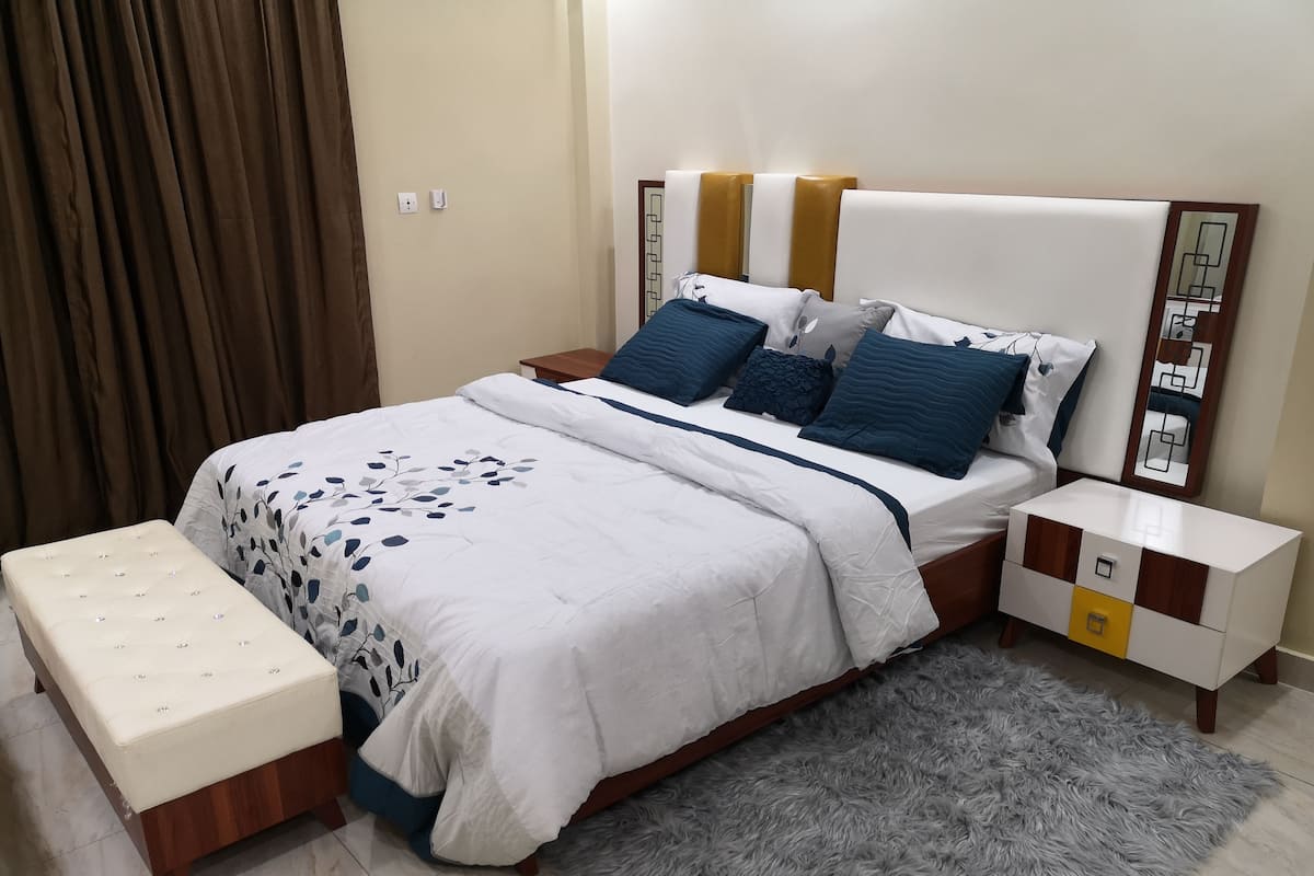 Ein Schlafzimmer mit einem Bett, Nachttischen, einer Bank und einem flauschigen Teppich.