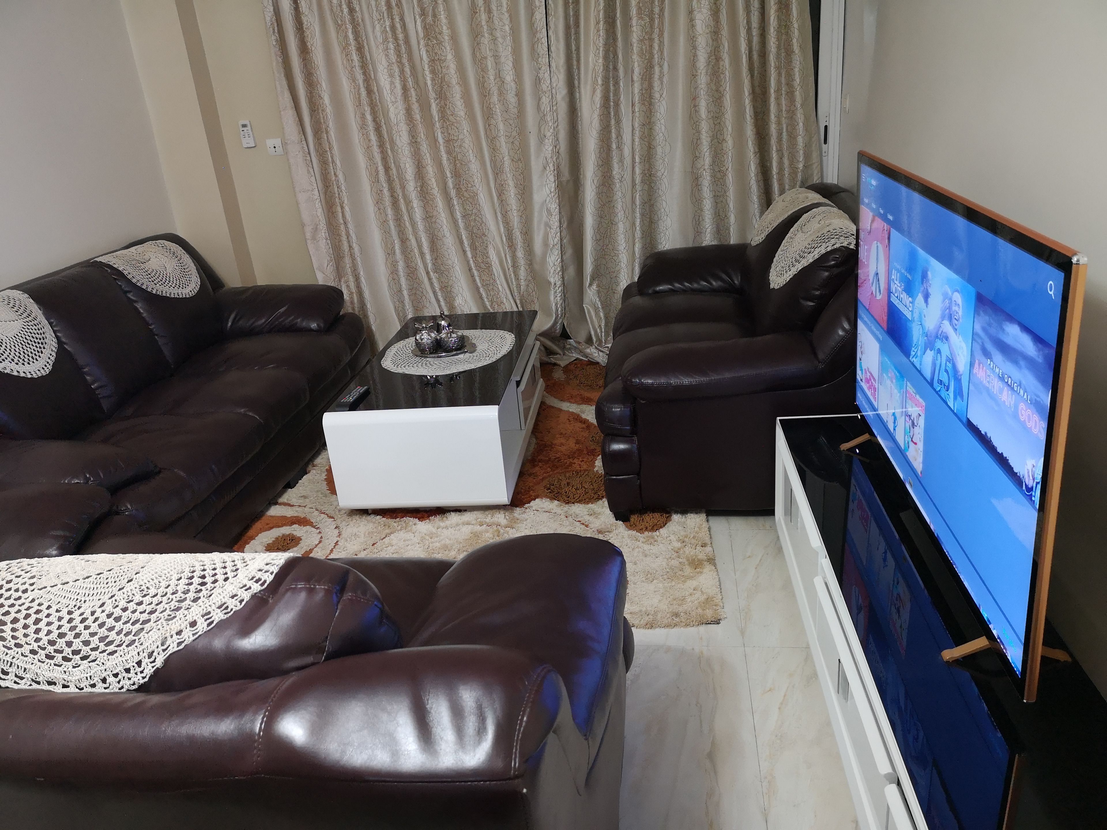 A living room with two brown leather sofas, a white coffee table, and a flat-screen TV on a stand.