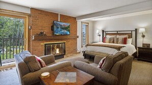 A modern hotel room with a fireplace, a large bed, a balcony, and a dining area. - Bear Claw 100 On Mountain Studio With Ski-In/Ski-Out Access! (Steamboat Springs)