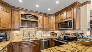 A kitchen with wooden cabinets, granite countertops, stainless steel appliances, and a built-in microwave. - Bear Claw 413 Premium On Mountain Condo With Ski-In/Ski-Out Access! (Steamboat Springs)