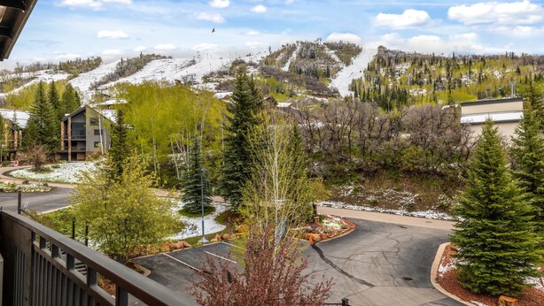 A residential area with a view of a snow-covered mountain, a parking lot, and a building with a modern design. - Bear Claw 413 Premium On Mountain Condo With Ski-In/Ski-Out Access! (Steamboat Springs)