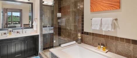 A modern bathroom with a large mirror, dark cabinets, a bathtub, and a shower area.
