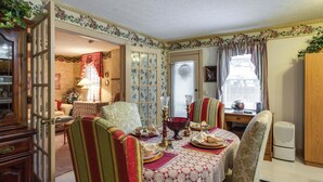 A dining area with a table set for two, a floral-patterned wall, and a door leading to another room.