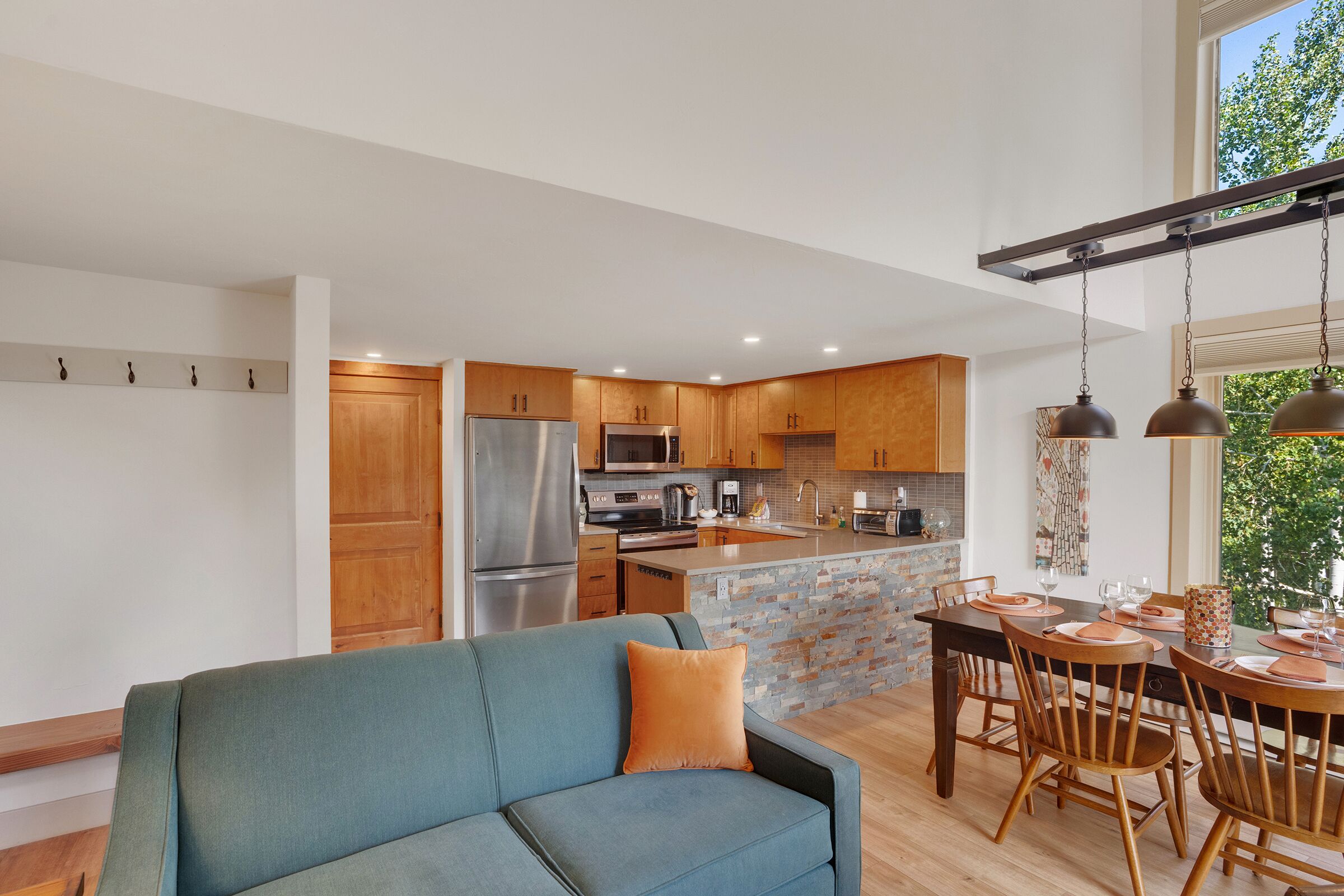 A modern kitchen with wooden cabinets, stainless steel appliances, and a dining area with a table and chairs.