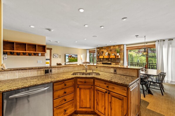 A kitchen with granite countertops, wooden cabinets, a stainless steel sink, and a built-in dishwasher.
