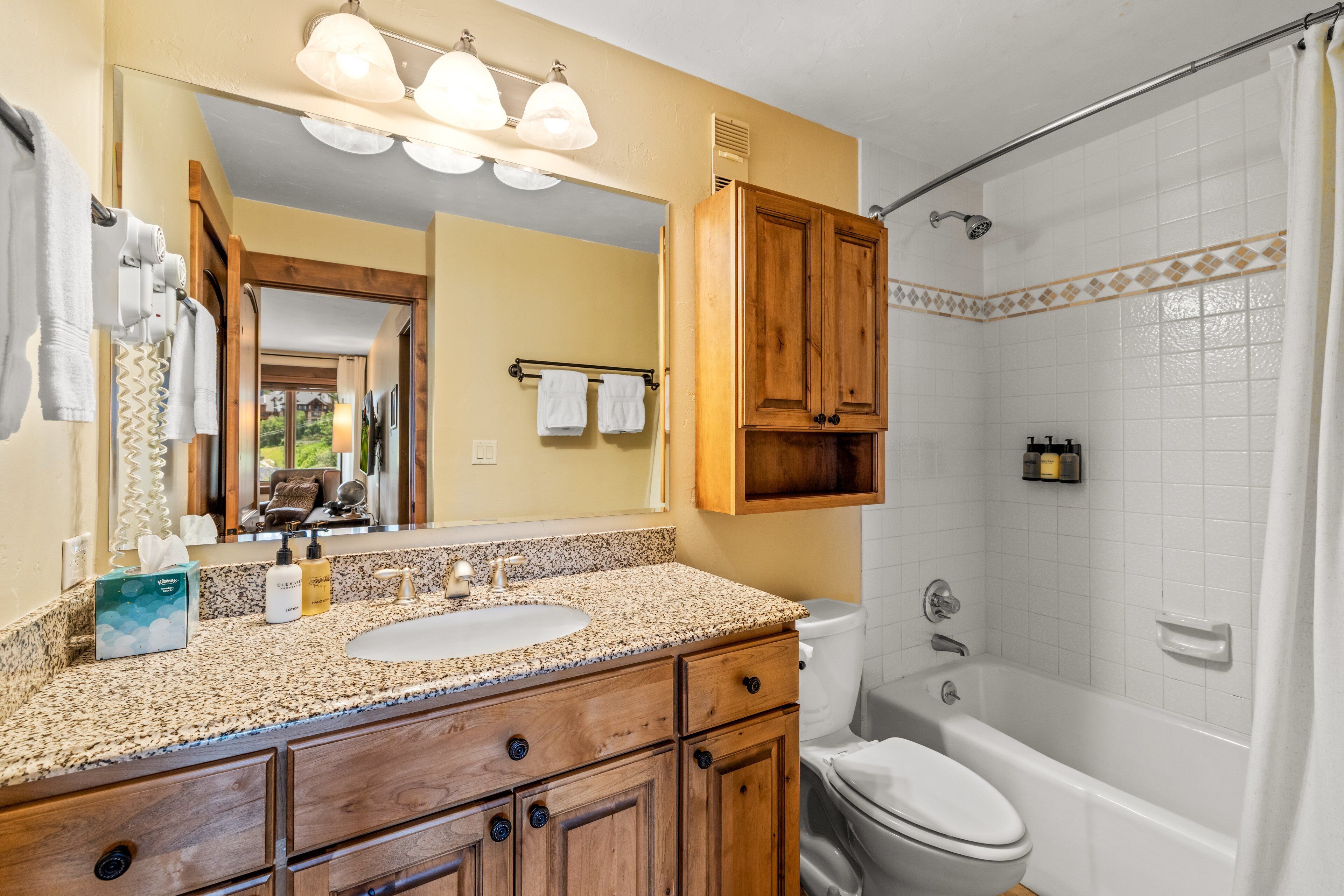A bathroom with a vanity, sink, mirror, and a shower area.