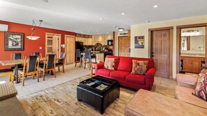 Ein geräumiges Wohnzimmer mit einem roten Sofa, einem Couchtisch und einem Essbereich mit Holzmöbeln.
