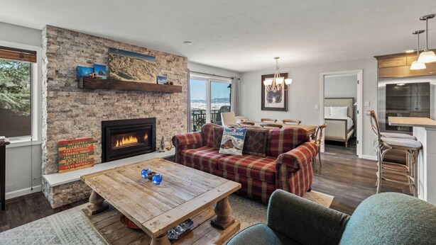 A cozy living room with a fireplace, a plaid sofa, and a wooden coffee table. - Bear Claw 109 on Mountain Condo with Ski-In/Ski-Out Access! (Steamboat Springs)