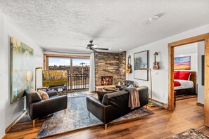 A modern living room with a fireplace, a sofa, a coffee table, and a view of the outdoors. - Bear Claw 514 Platinum Rated On Mountain Condo With Ski-In/Ski-Out Access! (Steamboat Springs)