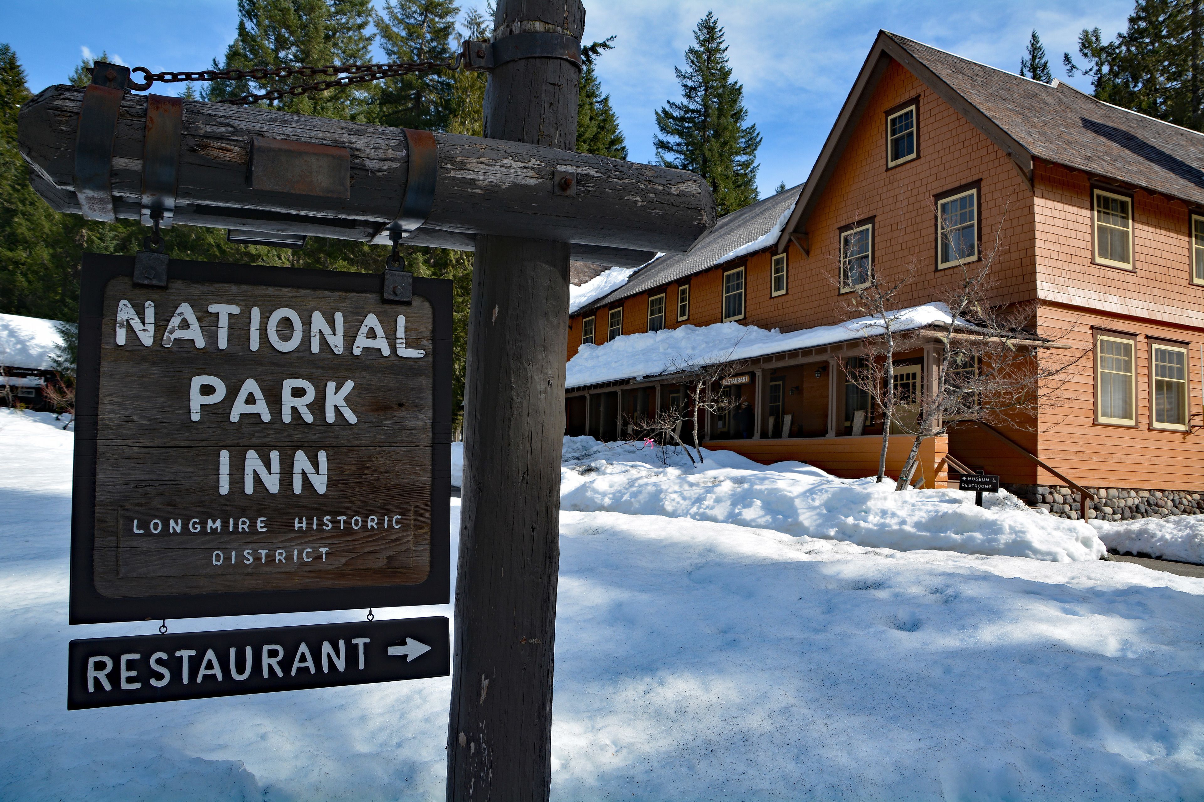 Un letrero de madera del National Park Inn en el Distrito Histórico de Longmire, indicando el camino hacia un restaurante.