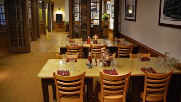 A restaurant with multiple tables and chairs, a wooden floor, and framed pictures on the walls.