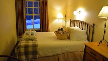 A hotel room with a bed, a bedside table, a lamp, a window with curtains, and a view of the outside.