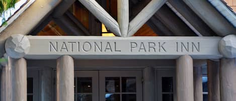 La entrada al National Park Inn, con un cartel sobre las puertas y columnas de madera.